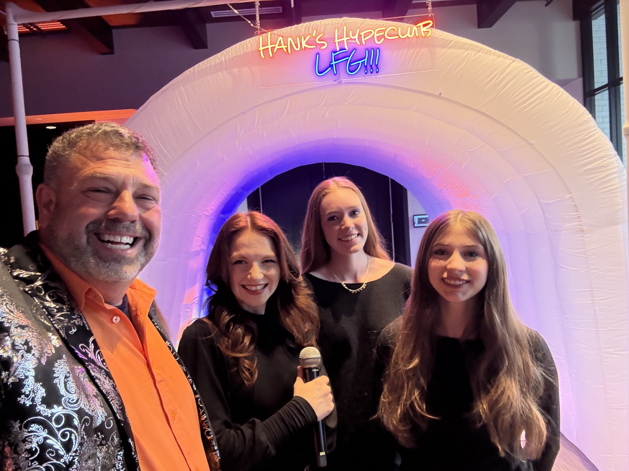 Hank's Basketball Themed Bar Mitzvah Group of smiling people standing under a colorful inflatable arch with a neon sign.