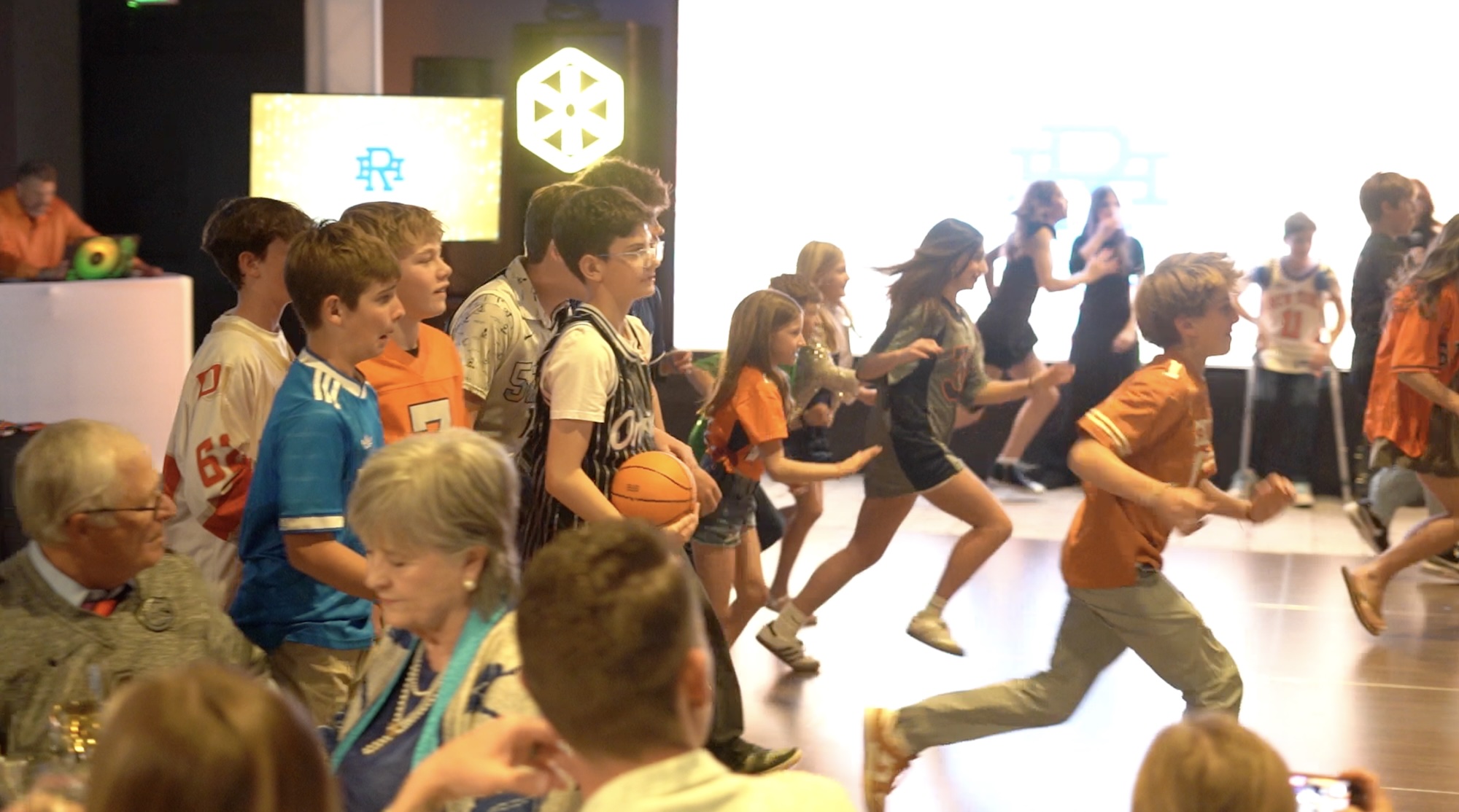 Hank's Basketball Themed Bar Mitzvah Energetic children and teens participating in a basketball-themed bar mitzvah, with adults observing in the foreground.